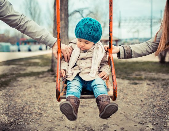Child on a swing, inbetween her divorced parents