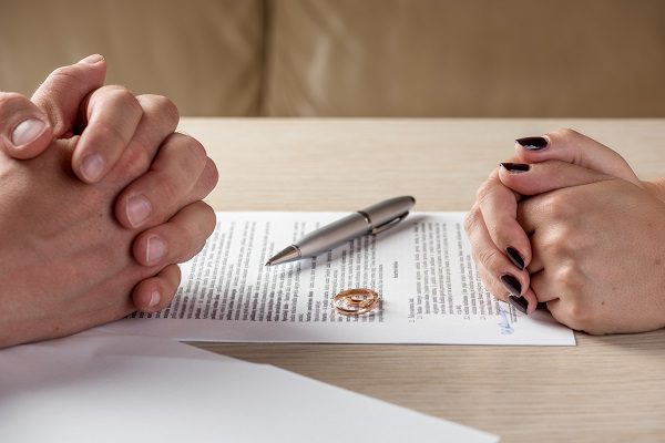 Hands of wife and husband signing divorce documents